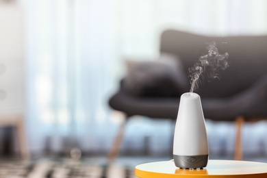 Aroma oil diffuser on table against blurred background. Air freshener