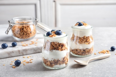 Photo of Jars with yogurt, berries and granola on  table