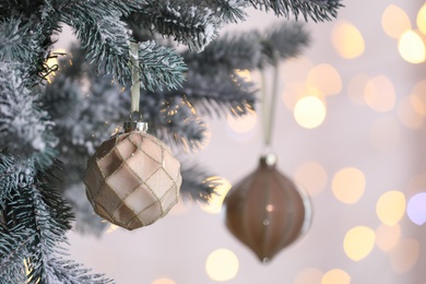 Christmas tree decorated with holiday baubles against blurred lights, closeup