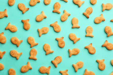 Photo of Delicious goldfish crackers on turquoise background, flat lay