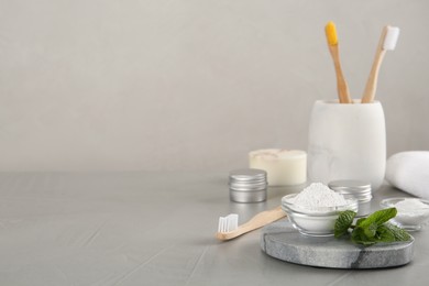 Composition with tooth powder and mint on grey table, space for text