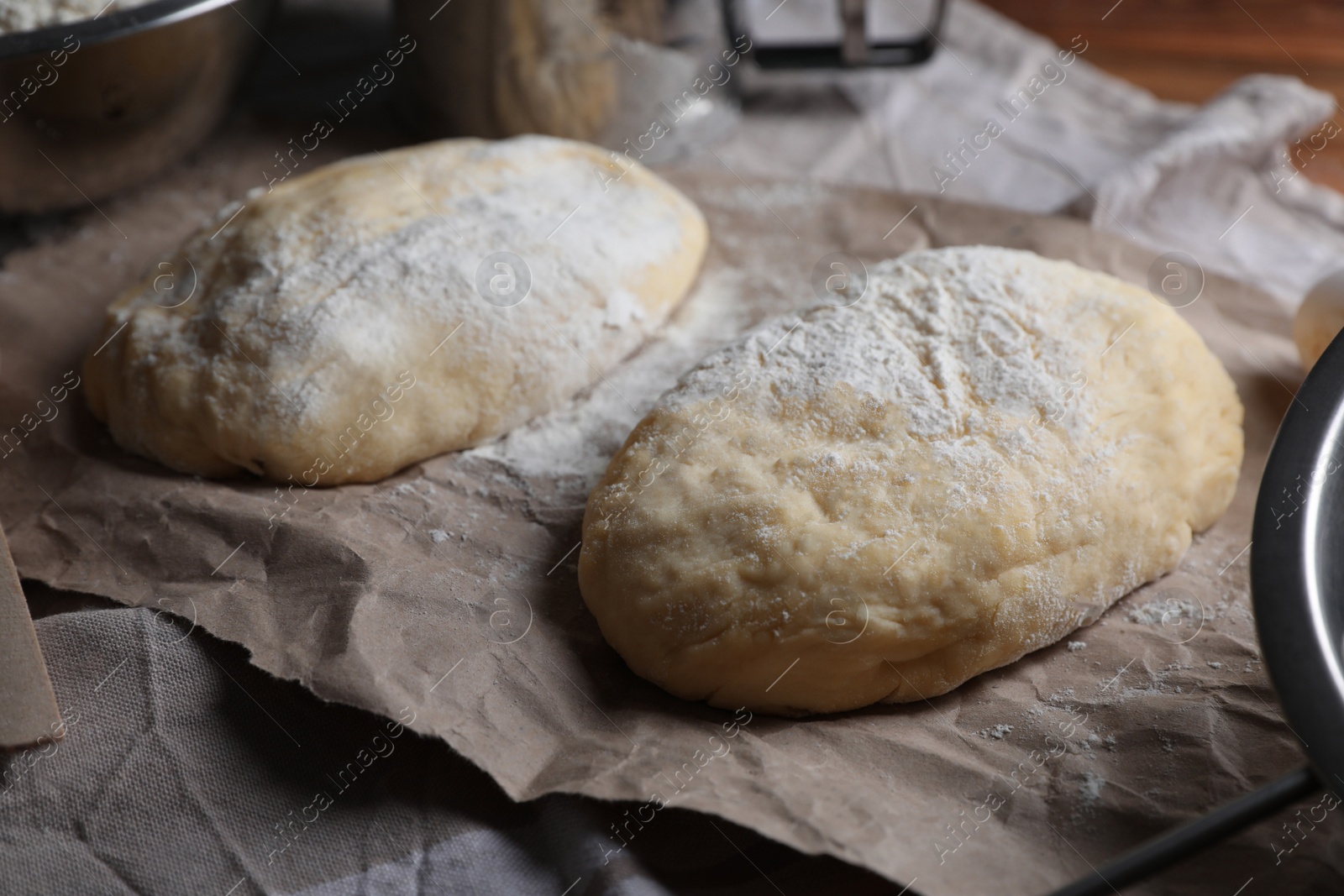 Photo of Raw dough and flour on parchment paper. Cooking ciabatta