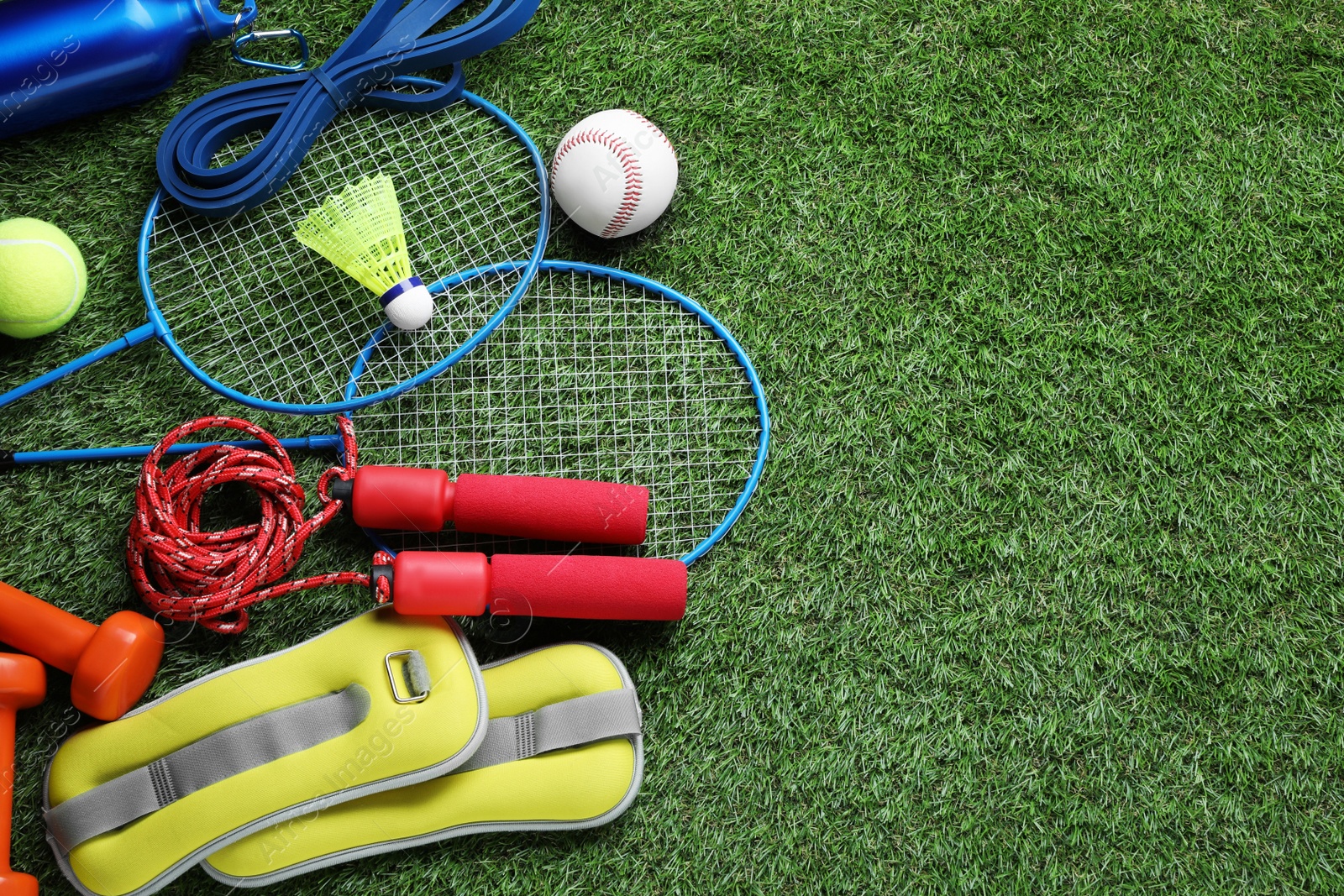 Photo of Set of different colorful sports equipment on green grass, above view. Space for text