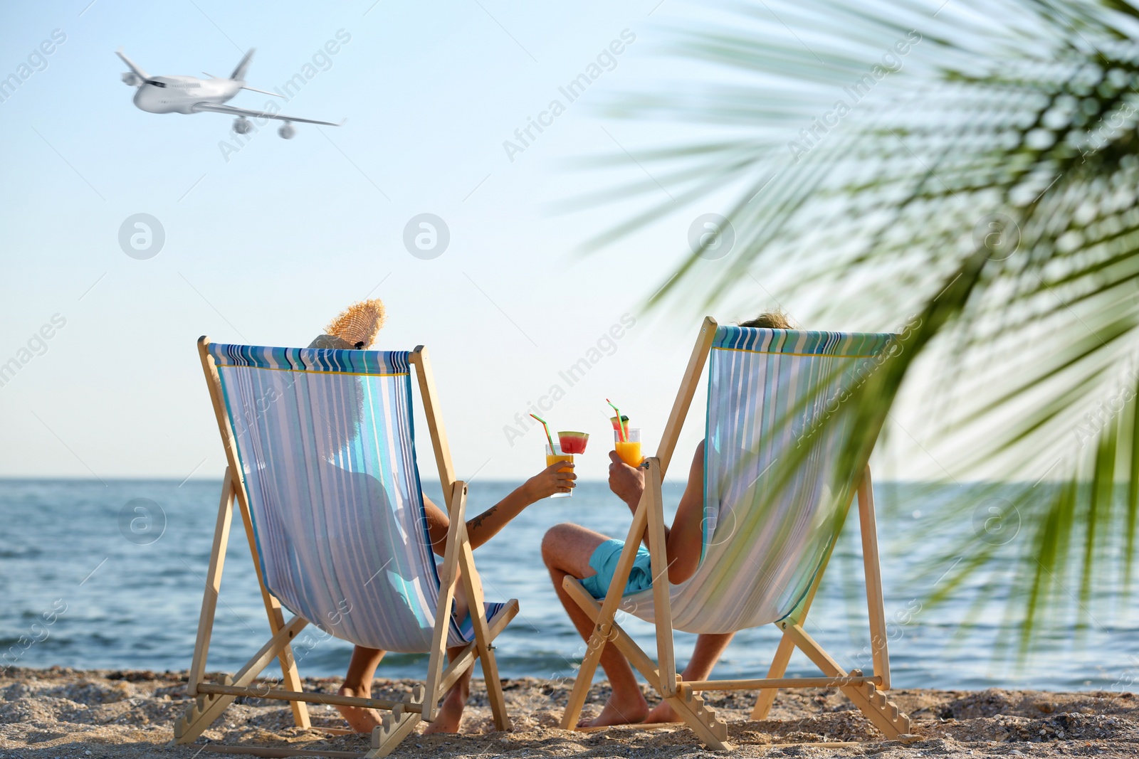 Image of Young couple with cocktails at seacoast and airplane in sky. Summer vacation