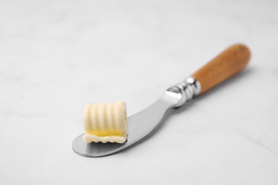 Photo of Tasty butter curl and knife on white table, closeup