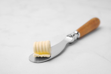 Tasty butter curl and knife on white table, closeup