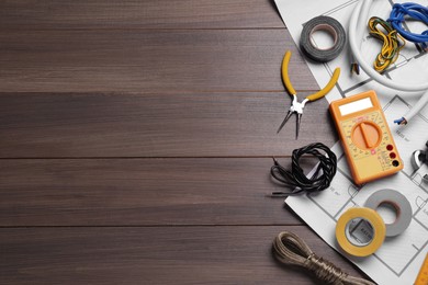Photo of Different wires and electrician's tools on wooden table, flat lay. Space for text