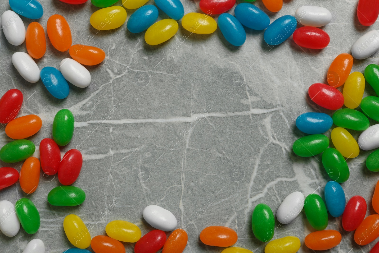 Photo of Frame of jelly beans on stone background, top view. Space for text