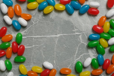 Photo of Frame of jelly beans on stone background, top view. Space for text