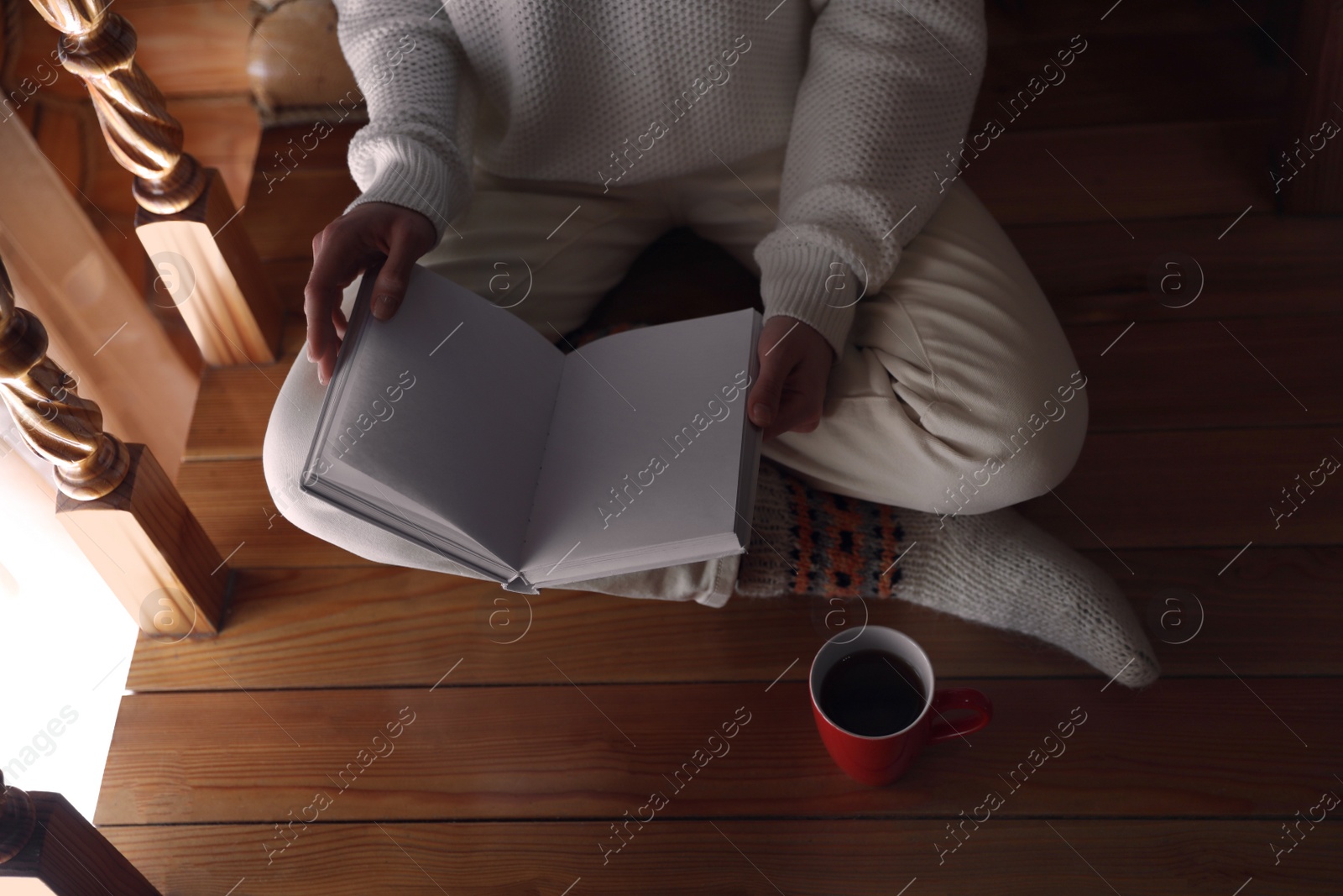 Photo of Woman with cup of coffee reading book at home, closeup