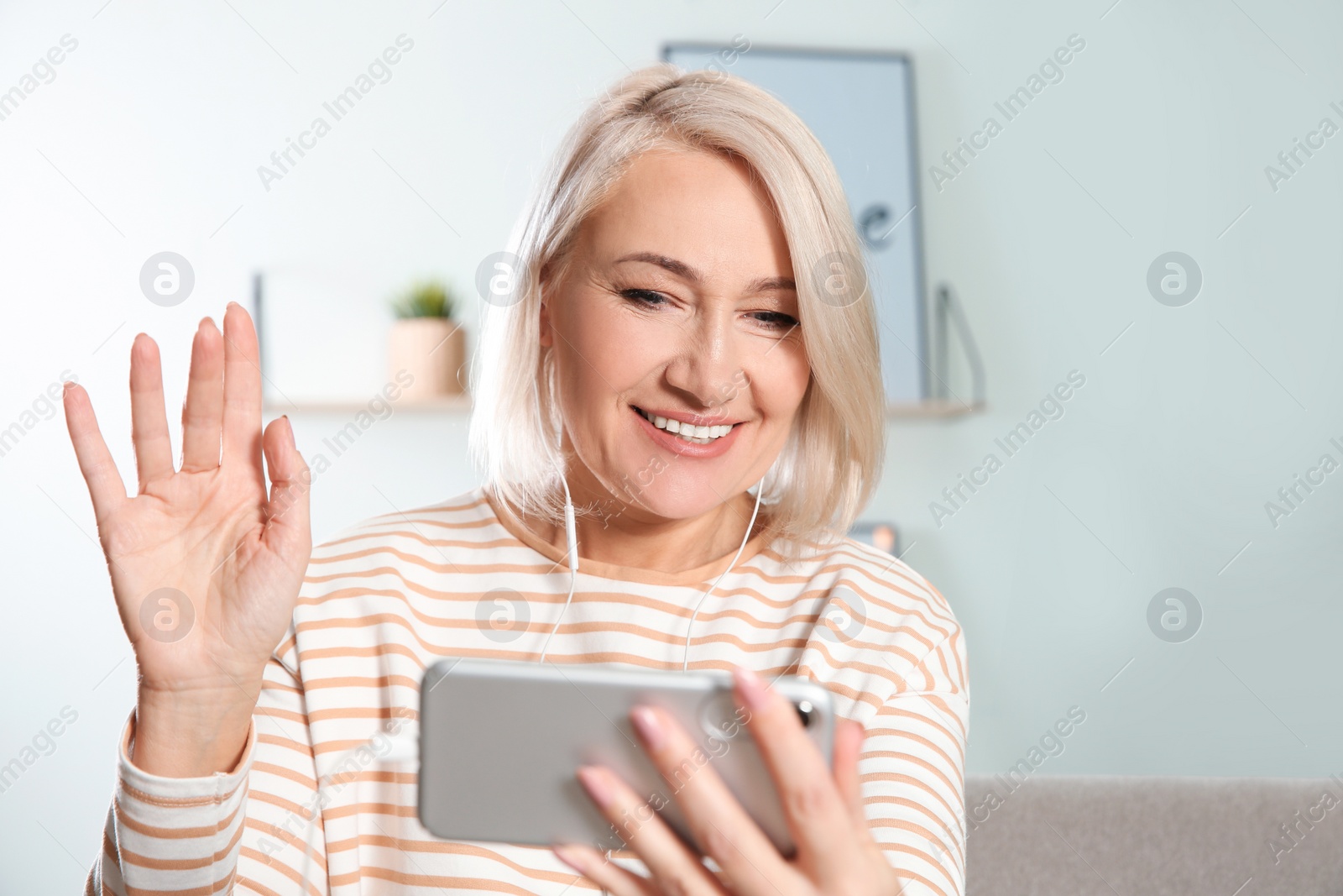 Photo of Mature woman using video chat on mobile phone at home