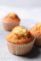 Photo of Delicious sweet muffins on light grey textured table, closeup. Space for text