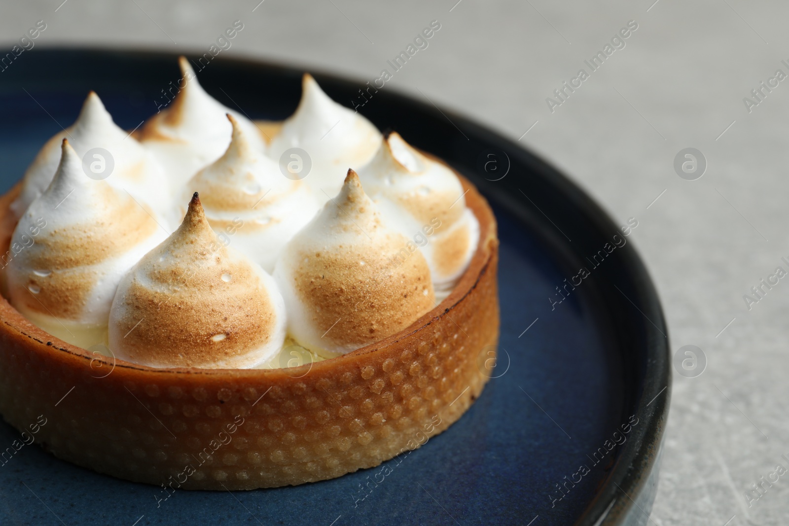 Photo of Tartlet with meringue on grey table, closeup and space for text. Delicious dessert