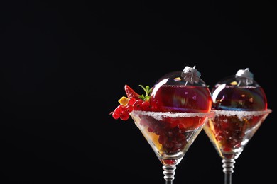Creative presentation of Christmas Sangria cocktail in baubles and glasses on black background, closeup. Space for text