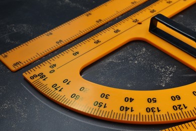 Photo of Protractor and ruler with measuring length and degrees markings on blackboard, closeup