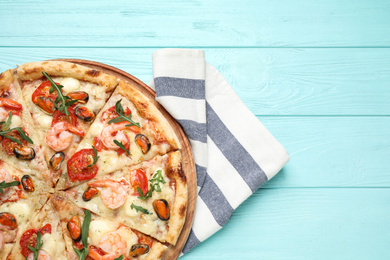 Photo of Delicious seafood pizza on light blue wooden table