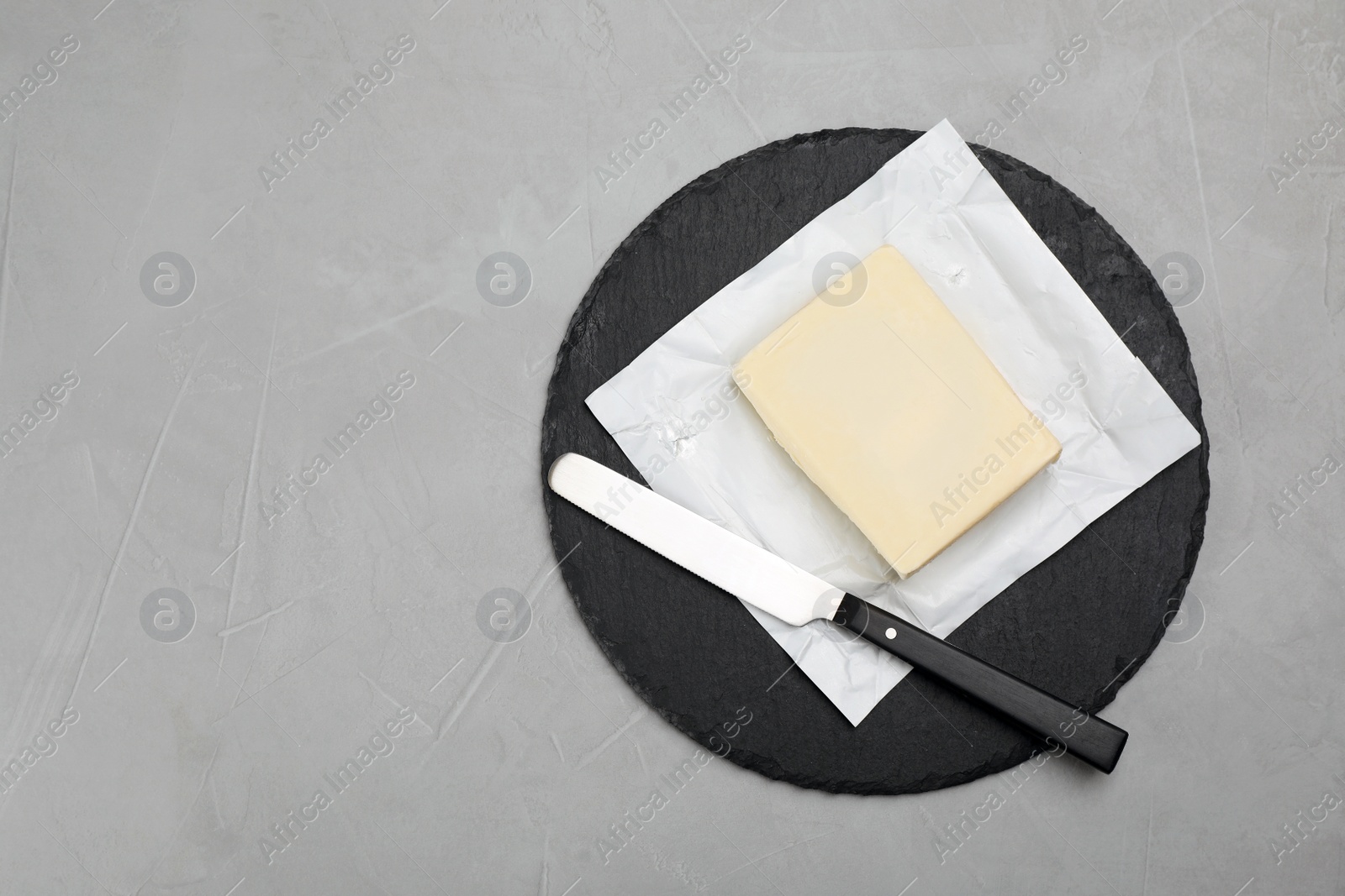 Photo of Slate plate with tasty fresh butter and knife on table, top view