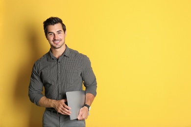 Photo of Young male teacher with laptop on yellow background. Space for text