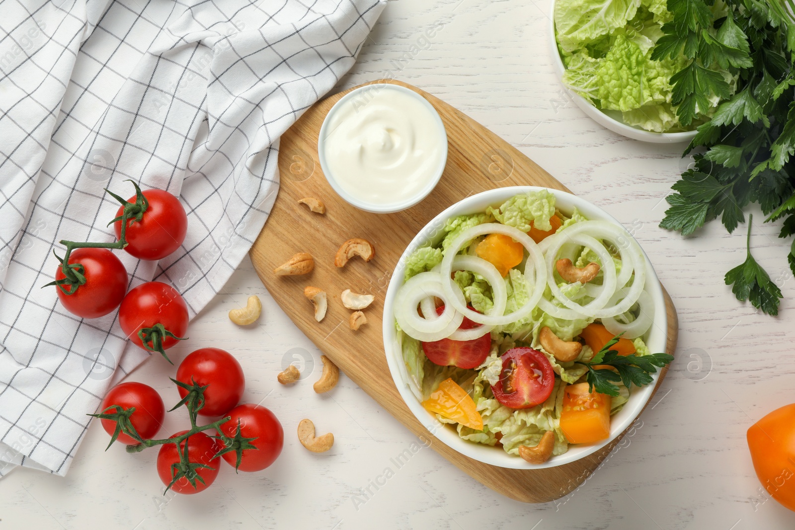 Photo of Bowl of delicious salad with Chinese cabbage and different ingredients on white wooden table, flat lay