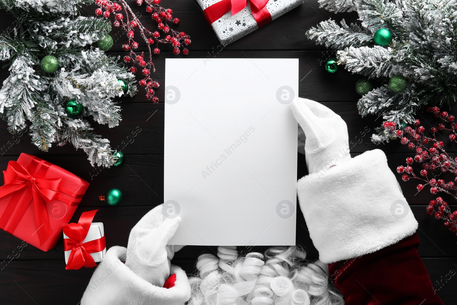 Photo of Santa Claus with letter at wooden table, top view. Space for text