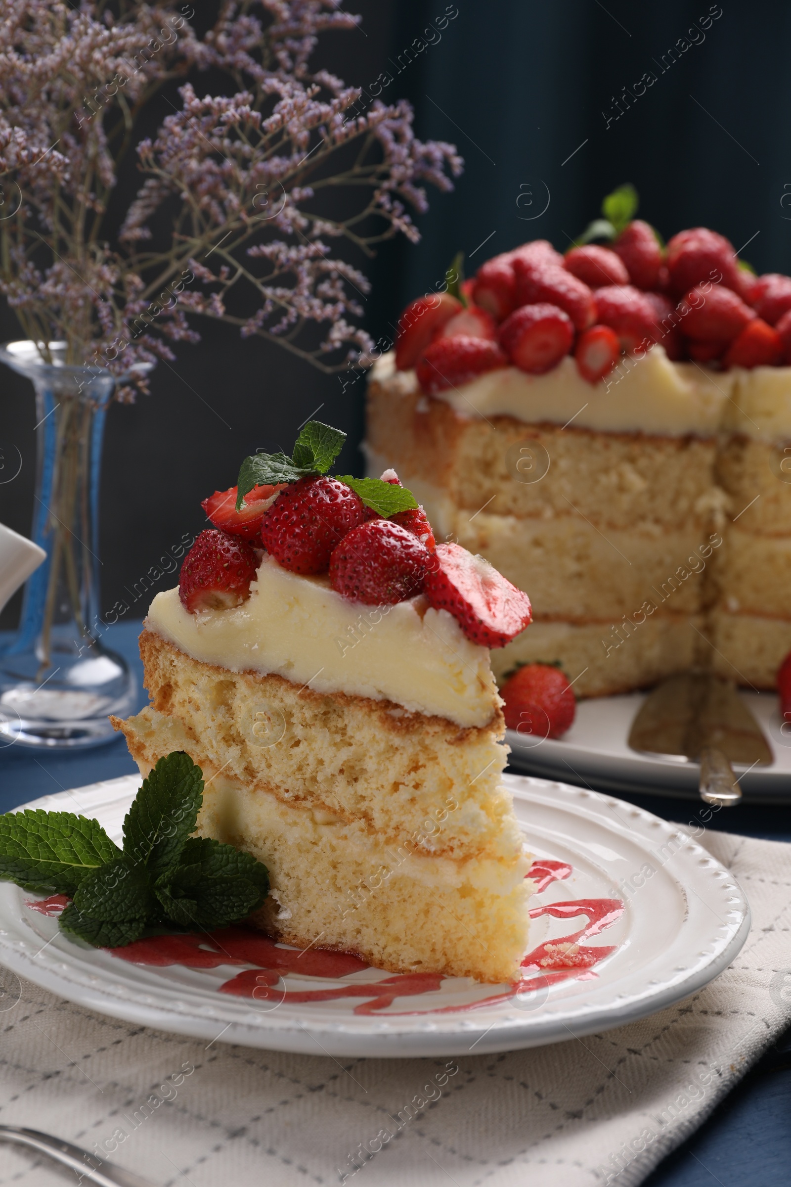 Photo of Piece of tasty cake with fresh strawberries and mint on blue wooden table