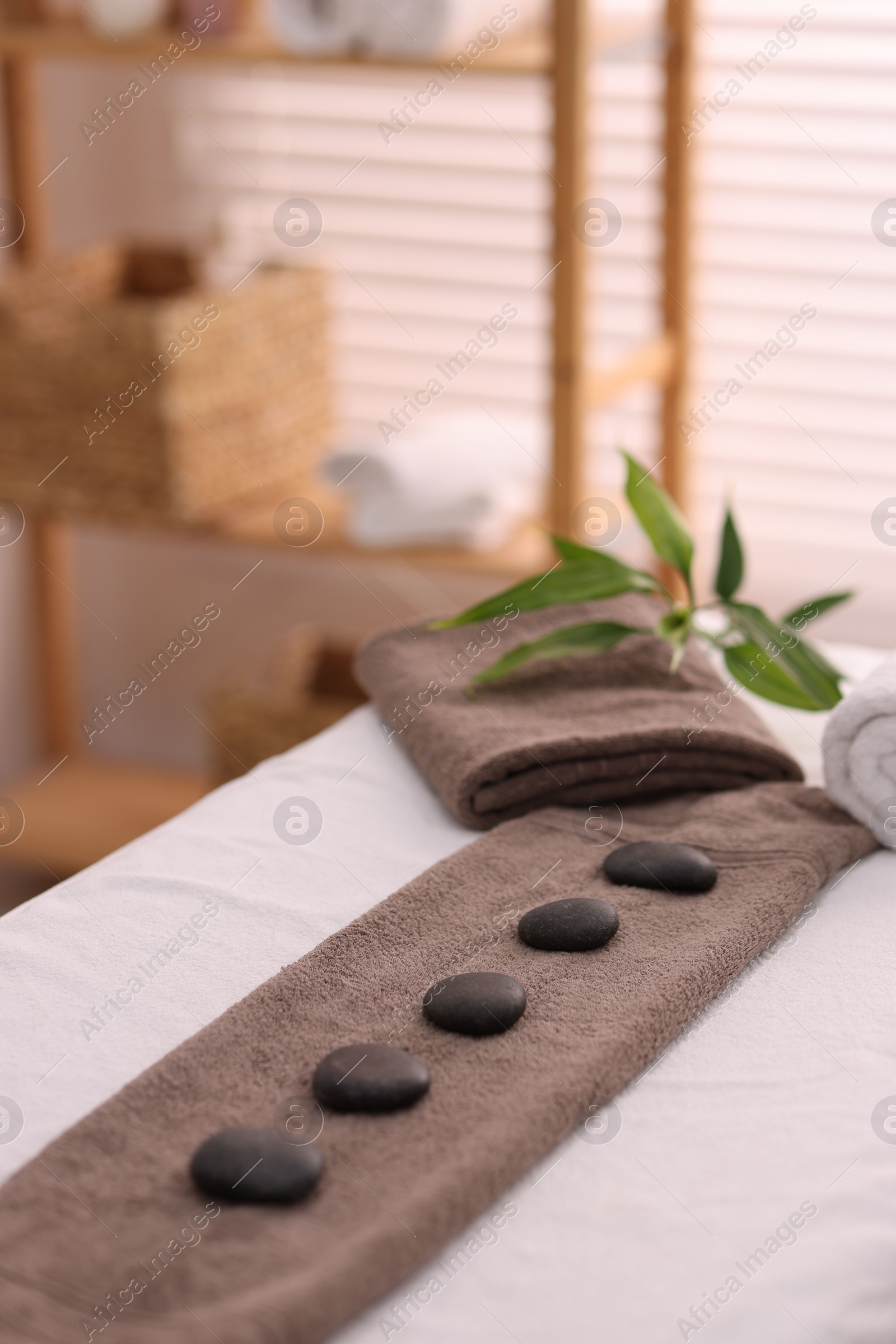 Photo of Towel with arranged spa stones on massage table in recreational center