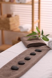 Photo of Towel with arranged spa stones on massage table in recreational center