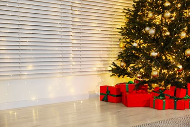 Photo of Beautifully wrapped gift boxes under Christmas tree indoors. Space for text