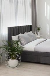 Photo of Stylish bedroom interior with comfortable bed and beautiful houseplants