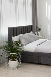 Stylish bedroom interior with comfortable bed and beautiful houseplants