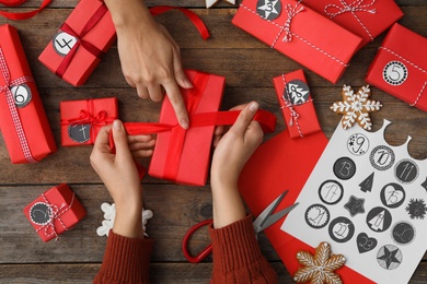 Photo of Women decorating gift box at wooden table, top view. Creating advent calendar