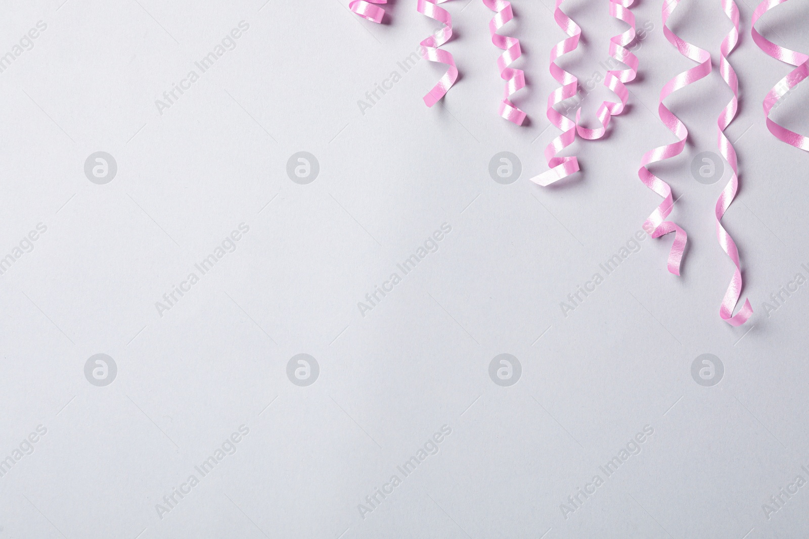 Photo of Pink serpentine streamers on light background, flat lay. Space for text