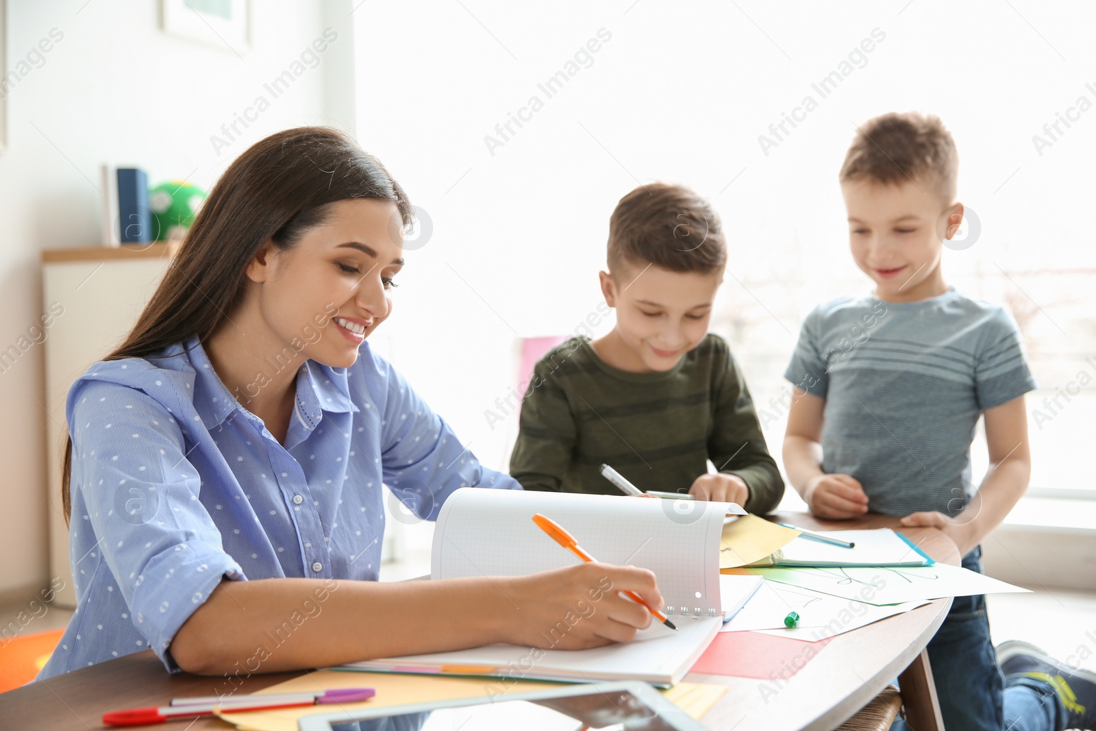 Photo of Cute little children with teacher in classroom at school