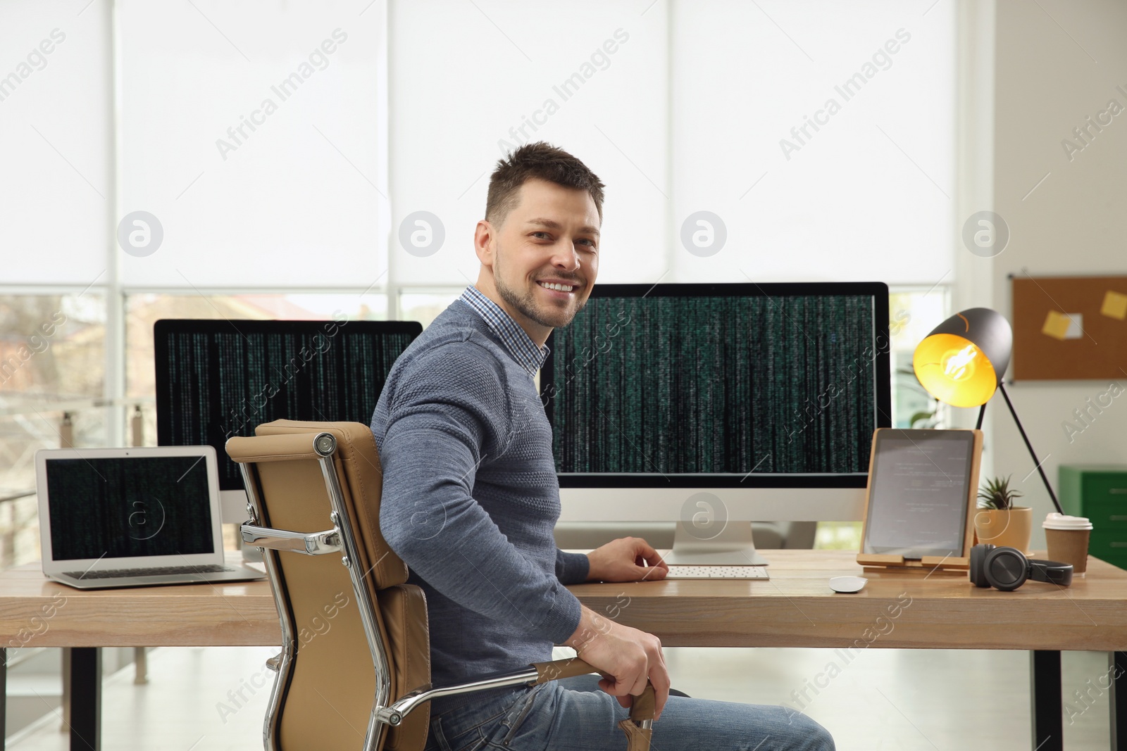 Photo of Happy programmer working at desk in office