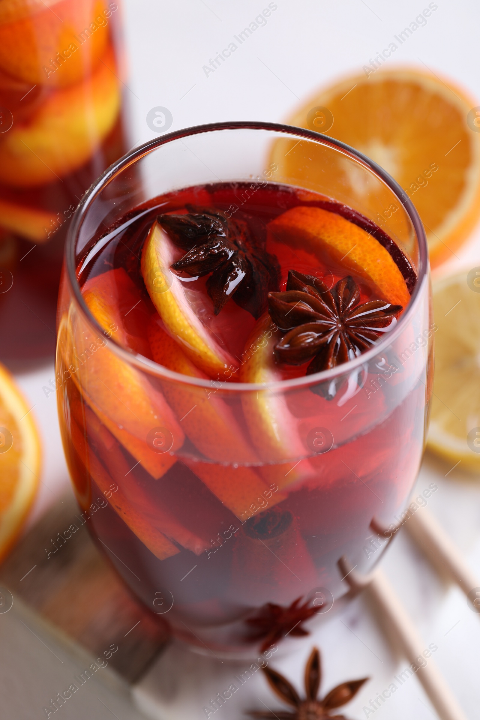 Photo of Aromatic punch drink and ingredients on white table, closeup