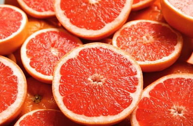 Many sliced fresh ripe grapefruits as background, closeup