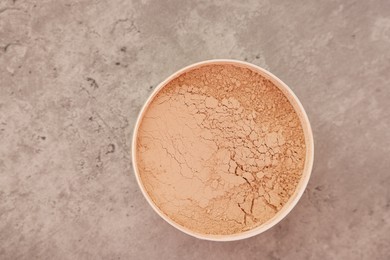 Photo of Face powder on grey textured table, top view. Space for text