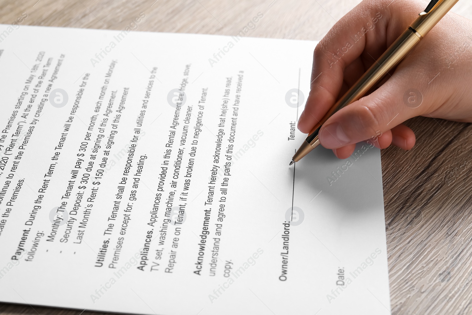 Photo of Woman signing document with pen at wooden table, closeup