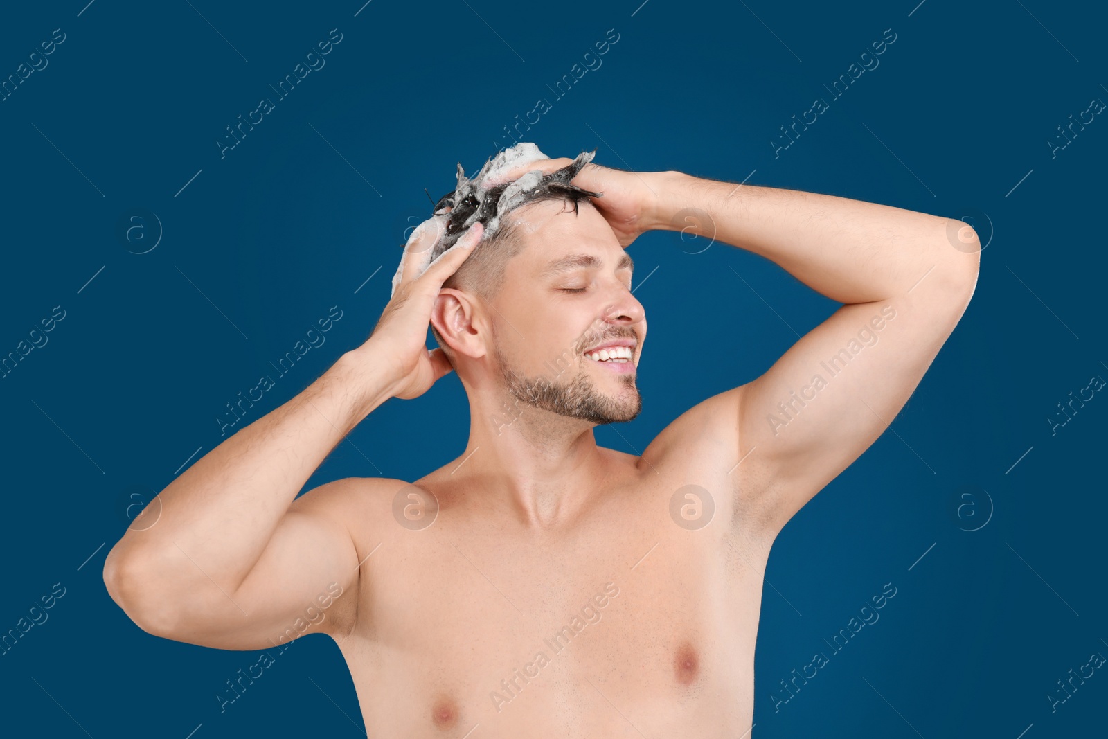 Photo of Handsome man washing hair on blue background