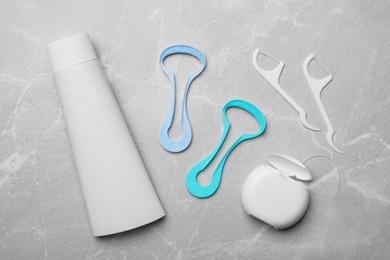 Flat lay composition with tongue cleaners and teeth care products on grey background