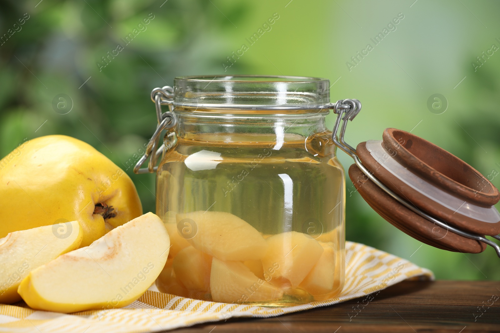 Photo of Delicious quince drink and fresh fruits on wooden table against blurred background, closeup