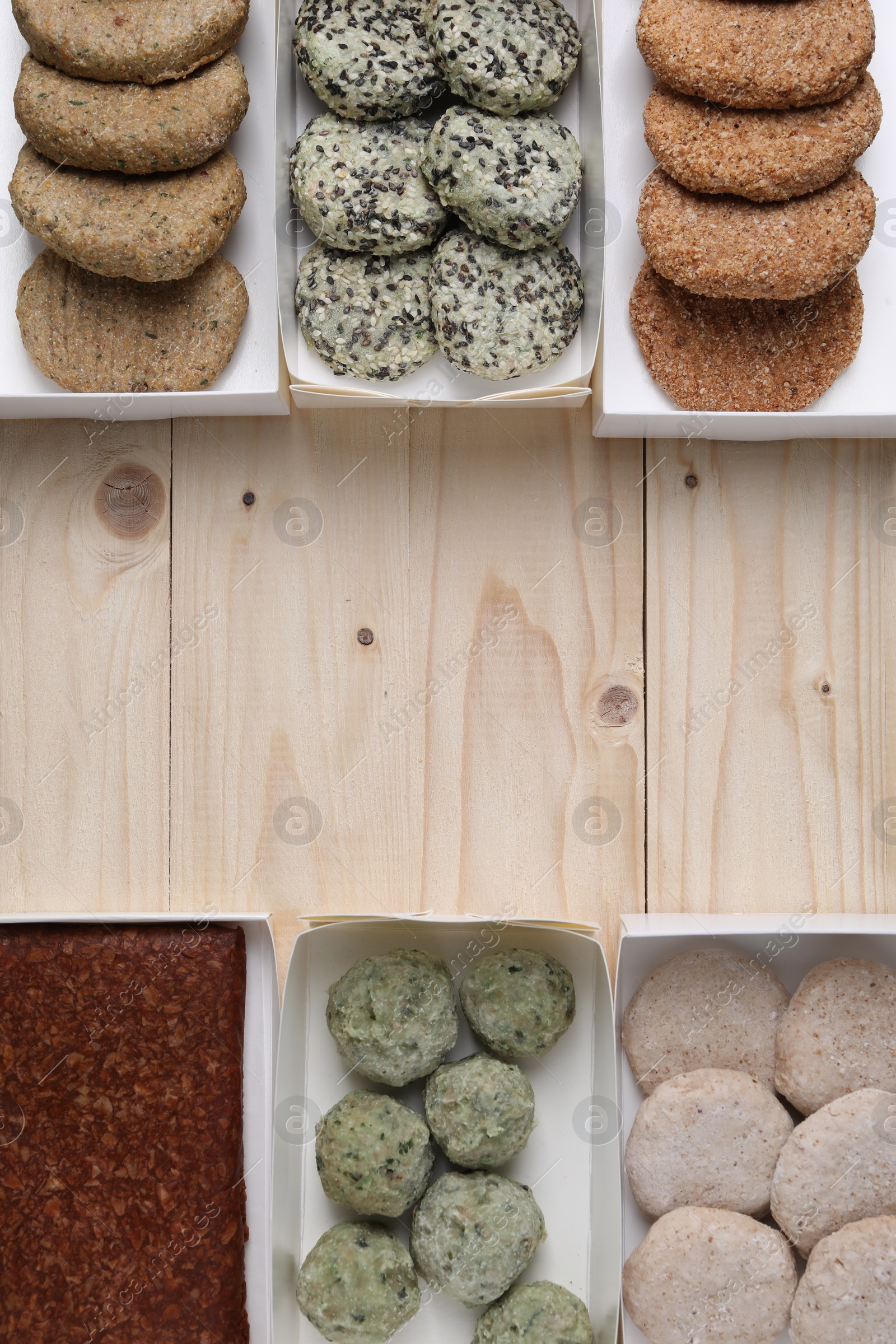 Photo of Many different raw vegan meat products on wooden table, flat lay. Space for text