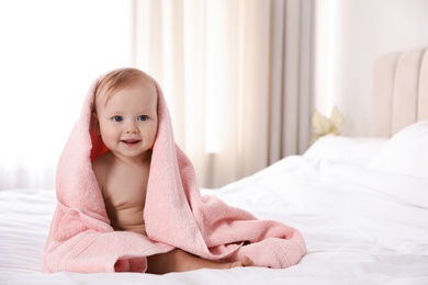 Photo of Cute little baby with soft pink towel on bed after bath. Space for text 