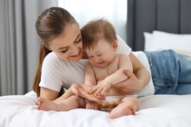 Happy mother with her baby on bed at home