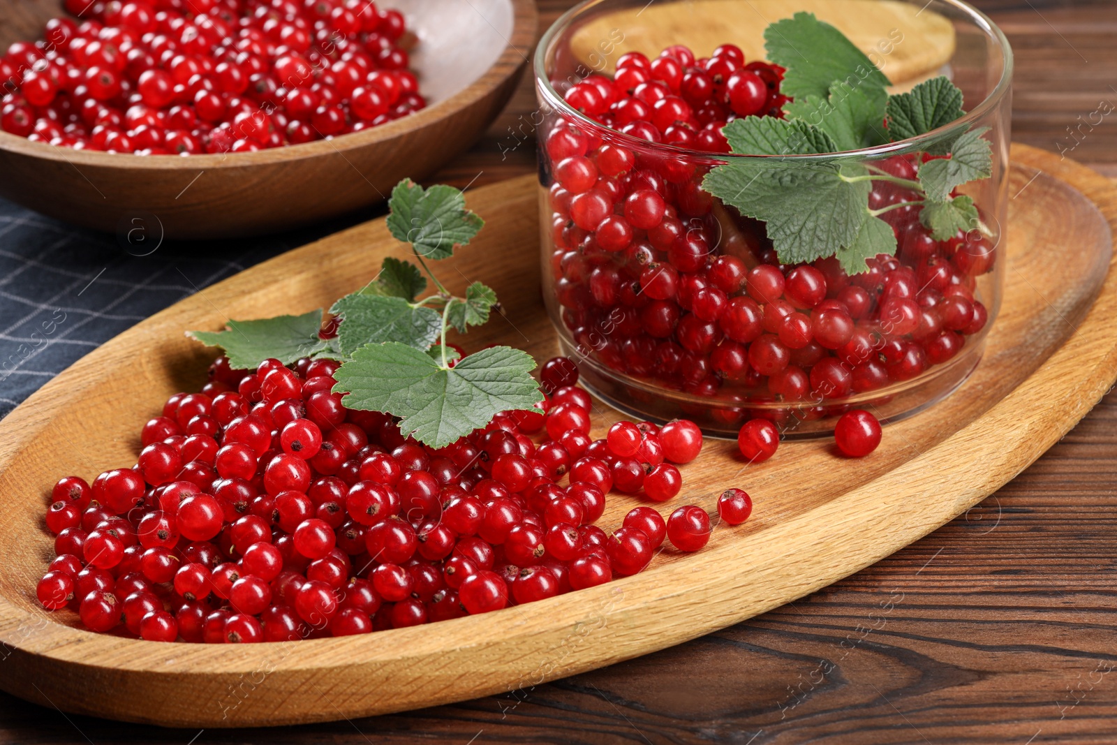 Photo of Ripe red currants and leaves on wooden table, closeup