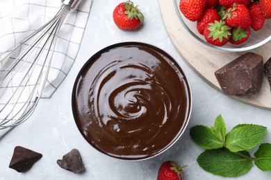 Photo of Delicious chocolate cream with strawberries and mint on light grey marble table, flat lay