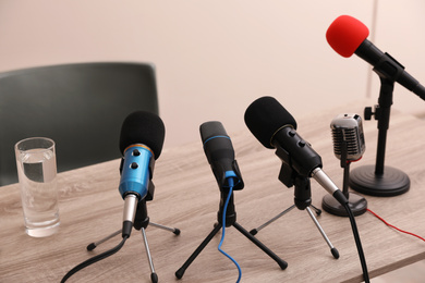 Journalist's microphones on wooden table in room