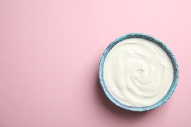 Photo of Bowl with creamy yogurt and space for text on color background, top view