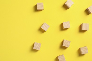 Photo of Blank wooden cubes on yellow background, flat lay. Space for text