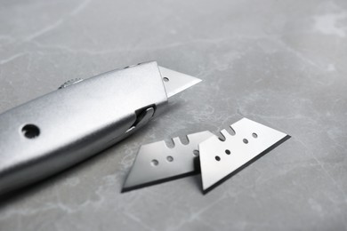 Photo of Utility knife and blades on light grey table, closeup